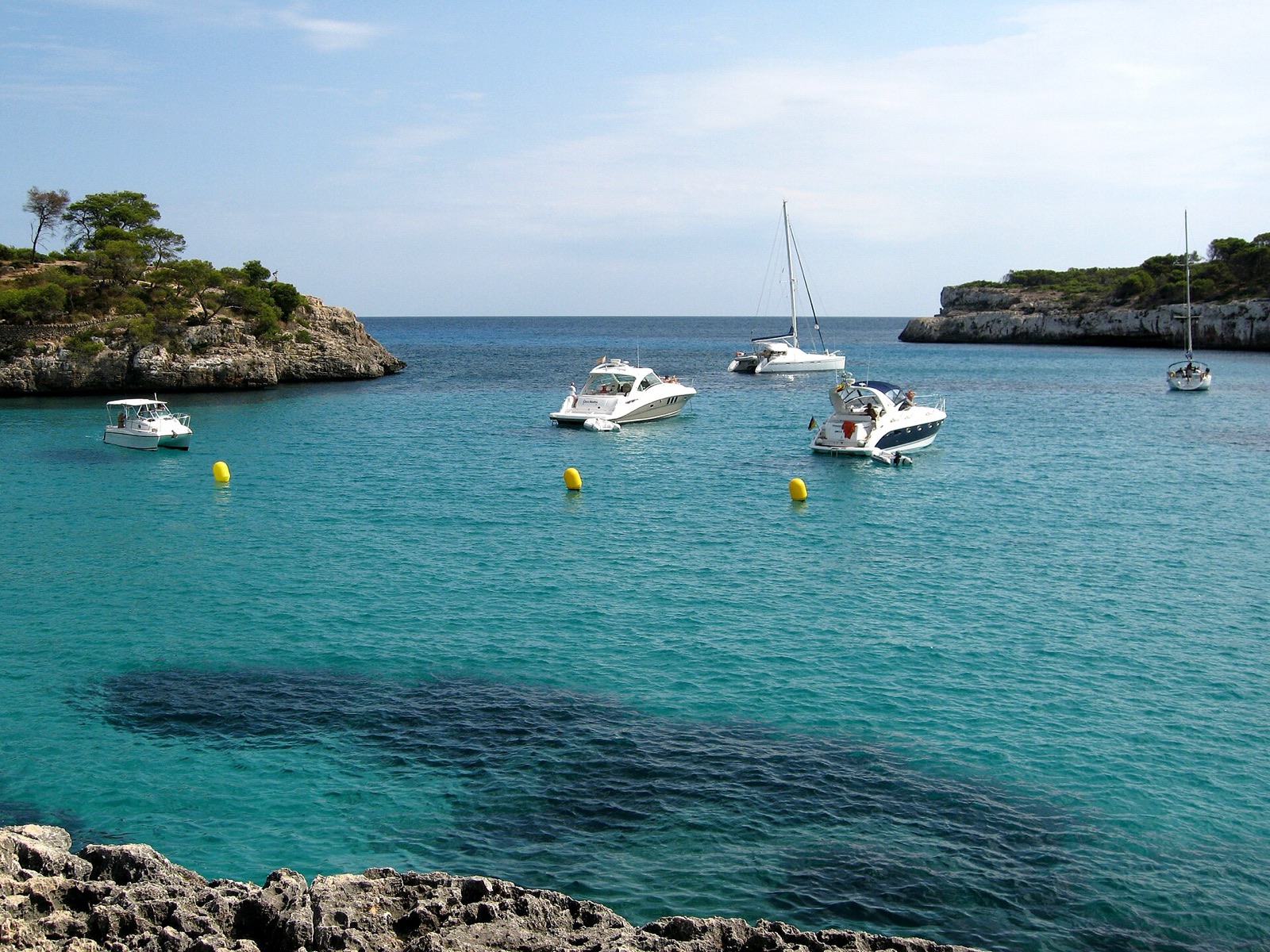Clear water and moored boats at Cala Mondragó, Santanyí
